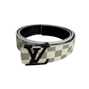 Louis Vuitton rutig skinnbälte - Snyggt Louis Vuitton bälte i svart och beige skinn med klassiskt rutigt Damier-mönster. Bältet har en stilren svart LV-logga som spänne och är tillverkat i Spanien. Perfekt accessoar för att lyfta din outfit med exklusiv känsla.