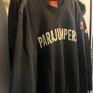Mörkblå sweatshirt från Parajumpers - Snygg mörkblå sweatshirt från Parajumpers med stort vitt tryck över bröstet och patch på ärmen. Tröjan har rund hals, långa ärmar och är gjord i mjuk bomull. Perfekt för dig som gillar streetwear och vill ha en clean look.