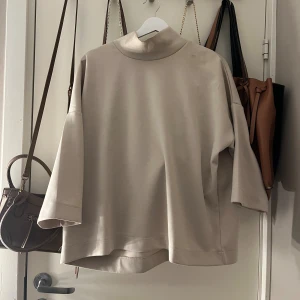 Beige polotröja från Carin Wester - Snygg beige polotröja från Carin Wester med loose passform och trekvartsärmar. Tröjan har en hög krage och är tillverkad i mjuk bomull. Perfekt för dig som gillar minimalistisk stil och vill ha något som är både chill och trendigt. Lite fläckar på framsidan men går förmodligen bort i tvätten💕