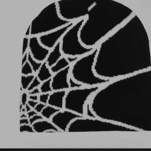 Svarta y2k spider mössa - Cool svart mössa med vitt spindelnätsmönster som ger en edgy vibe. Perfekt för dig som vill sticka ut och gillar unika detaljer. Materialet är stickat och passar bra under höst och vinter.