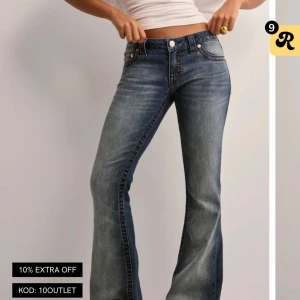 Blå bootcut jeans från True Religion - Snygga blå jeans från True Religion med bootcut passform och låg midja. Jeansen har klassiska fickor med dekorativa sömmar och logopatch bak. Materialet är slitstarkt denim med lätt tvättad look och dragkedja fram.