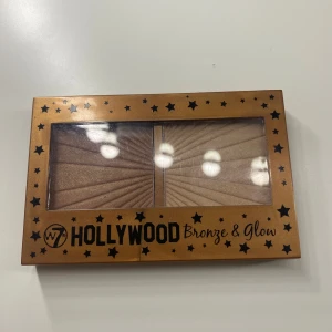 W7 Hollywood Bronze & Glow duo - Snygg contourpalett från W7 med två pressade puder: en varm bronzer i bronsbrun nyans och en champagnefärgad highlighter. Kommer i en guldig ask med spegel och stjärndetaljer. Perfekt för att skapa glow och markerade ansiktsdrag. Har bara testats på.