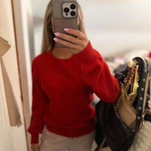 Röd stickad tröja med rund hals - En klassisk röd stickad tröja med rund halsringning och långa ärmar. Tröjan har ribbade muddar vid ärmslut och nederkant, vilket ger en snygg och enkel look. Perfekt för dig som vill ha en färgstark bas i garderoben. Står ingen storlek men passa mig som bruka ha S 