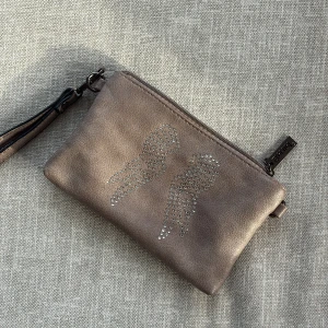 Brun kuvertväska med strassvingar - Snygg brun kuvertväska från Eternal i skinnimitation med strassdetaljer i form av vingar på framsidan. Väskan har handledsrem, dragkedja upptill och extra fack med dragkedja på baksidan. Perfekt storlek för mobilen och småsaker.