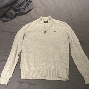 Beige stickad half zip-tröja Morris - Snygg beige stickad tröja från Morris med half zip och ribbade muddar. Tröjan har en liten broderad logga på bröstet. Nypriset på denna tröja ligger på 2000 mitt pris 850. Tröjan är nyskick och endast använd 2-3 gånger, om ni har några fler frågor är det bara att höra av sig!