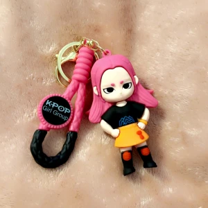 KPOP Girl Group Nyckelring - Färgglad nyckelring med en söt figur inspirerad av KPOP girl groups. Tillverkad i mjuk silikon med rosa och svarta detaljer, perfekt som accessoar till väskan eller nycklarna. Produkten är i nyskick utan synligt slitage.