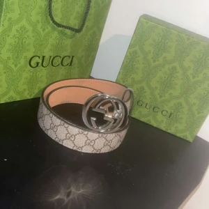  GG Supreme bälte med silverdetalj - Säljer ett  GG Supreme bälte med klassiskt monogrammönster i beige och brunt. Bältet har en stor rund silverfärgad GG-spänne och är tillverkat i äkta skinn. Kommer med originalförpackning, dustbag och tag. Perfekt för att lyfta din outfit.