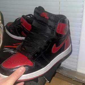 Jordan 1 Retro High OG “Bred Patent” - Sällan använda Jordan 1 Retro High OG med helt nya röda snören skorna helt nya är väldigt svåra att hitta och är väldigt sällsynta. Helt nya kostar skorna över 5000kr. Men nu har jag valt att sälja de till ett bra pris. Pris kan diskuteras 