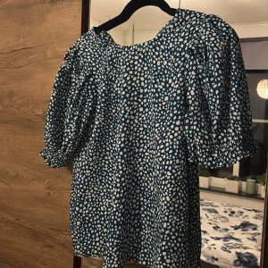Blåvit prickig blus med puffärm - Säljer en blå/ mörk turkos blus med vita prickar och puffiga korta ärmar med resår vid ärmslut. Knappt använd så mycket fint skick🥰