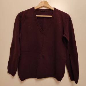 Herrysoft vinröd v-ringad stickad tröja - Vinröd stickad tröja från Herrysoft med v-ringad hals och långa ärmar. Mjuk och skön, perfekt för kyliga dagar. Enkel design utan mönster eller detaljer, passar dig som gillar stilrena plagg med lite loose fit.