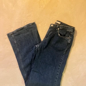 Mörkblå raka jeans från NA-KD - Låg midja jeans med vida ben. Användning syns längst ner på ena benets baksida (se bild två) Byxorna är köpta på NA-KD och de heter  ”jeans med låg midja” och har artikelnummer: 1018-008235-0116