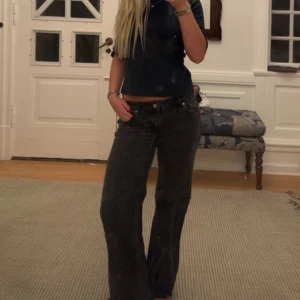 Svarta wide jeans från nakd  - Säljer ett par svarta jeans från nakd med klassisk femficksdesign och knappgylf. Modellen har en loose och wide passform med raka ben och låg midja. Jeansen är tillverkade i slitstarkt denim och har en cool, mörk tvätt som ger en avslappnad vibe.