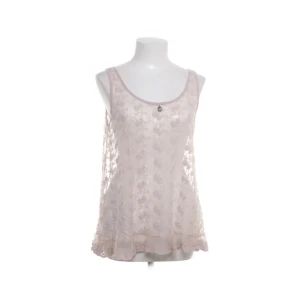 Beige broderad linnetopp från Ajlajk - Säljer en ljusrosa linnetopp från Ajlajk med broderade blommor och spetsdetaljer. Toppen är ärmlös och har rundad halsringning samt volangkant nedtill. Romantisk och bohemisk stil.