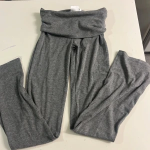 Grå ribbade leggings från Gina Tricot - Grå ribbade leggings från Gina Tricot med bred, vikt linning. Mjukt och stretchigt material som sitter skönt och följer kroppen. Perfekta för en chill och avslappnad stil. (Jag som är 156 så passar byxorna lite för små men 100% går att använda)