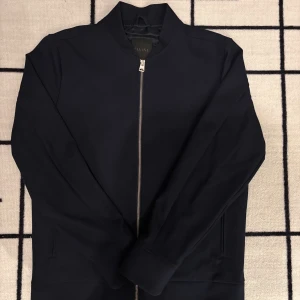 Elvine jacka  - Säljer en stilren mörkblå jacka från Elvine i storlek S. Jackan har klassisk rak passform, dragkedja framtill och diskreta fickor på sidorna. Insidan är fodrad med slätt tyg och har en innerficka med knapp. Den är använd ett fåtal gånger och har inga märken på användning och är som helt ny utan prislapp, ny pris va ca 2500kr hos MQ där den köptes. Skriv för mer info