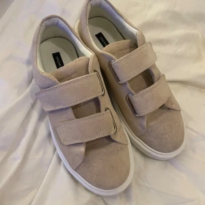 Beige sneakers från Sneaky Steve - Snygga beige sneakers från Sneaky Steve med två breda kardborreband och vit platt sula. Finns tecken på användning, se bilder! 