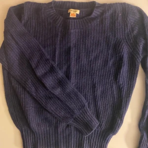 Mörkblå stickad tröja XS - Mysig mörkblå stickad tröja från Bellerose i ribbat material. Tröjan har rund halsringning och långa ärmar, perfekt för kyliga dagar. Klassisk och enkel modell som är lätt att matcha med olika outfits.