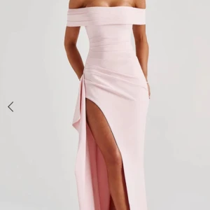 Ljusrosa offshoulder långklänning - Supersnygg ljusrosa långklänning med offshoulder och hög slits. Klänningen har en figurnära passform och markerad midja, perfekt för dig som vill sticka ut. Tunn och mjuk känsla i materialet, elegant och modern look.