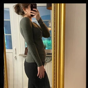 Mörkgrön långärmad topp - En enkel mörkgrön långärmad topp med rund halsringning. Modellen är figurnära och passar perfekt till jeans eller kostymbyxor.