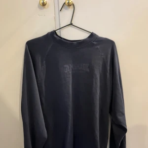 Mörkblå långärmad tröja från Gymshark - Säljer en mörkblå långärmad tröja från Gymshark i storlek XS. Tröjan har en enkel design med diskret Gymshark-logga framtill och rund halsringning. Perfekt för träning eller chill dagar. Passformen varierar, jag som bär M/L sitter den bra på då den har en oversized fit.