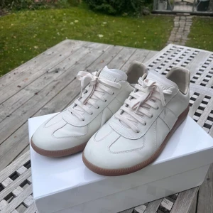 Maison Margiela vita sneakers - Maison Margiela sneakers i vitt skinn med klassisk gummisula. I skit bra skick! Storlek 43,  digitalt kvitto finns! Box medföljer.