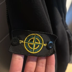 Svart quiltad jacka från Stone Island - Säljer en svart jacka från Stone Island med quiltad front och ärmar i mjuk bomull. Jackan har dragkedja, ribbade muddar och den klassiska logotypen på ärmen. Perfekt för dig som vill ha en stilren och modern look. Fråga om tydligare bilder.