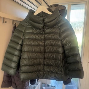 Grön pufferjacka från Herno - Säljer en mörkgrön pufferjacka från Herno i storlek 42 vilket motsvarar S/36. Jackan har en bred krage, horisontella quiltade sömmar och är tillverkad i 100% polyamid. Den har en loose passform och är perfekt för kalla dagar. Snygg och modern look med diskret logga på insidan. Köpt på vestiaire så äktighetsbevis medföljer