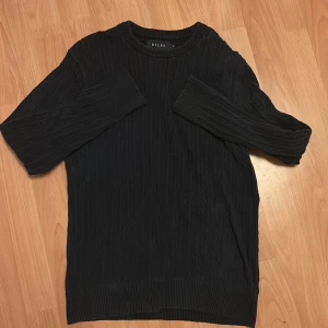 Svart stickad tröja från Riley - Svart stickad tröja från Riley i storlek S. Tröjan har ett klassiskt kabelstickat mönster, rund halsringning och långa ärmar. Perfekt för lager-på-lager under kyliga dagar och enkel att matcha med jeans