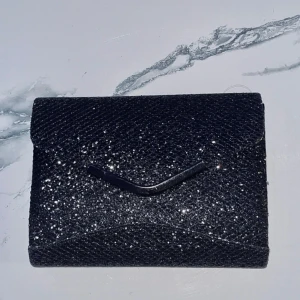 Svart glittrig kuvertväska med kedja - Liten svart glittrig axelväska i nyskick. 