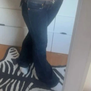 True Religion Joey Low Rise Flare Jeans - Säljer ett par mörkblå True Religion Joey jeans med låg midja och flare-ben, de är köpta på vinter men var tyvärr för stora för mig. Snygga detaljer på bakfickorna och de är slitna längst ner💞Middjemått rakt över: 40 cm Innerbenslängden: 81 cm 