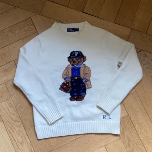 Polo Ralph lauren stickad tröja - En riktigt fin vit stickad tröja från Polo Ralph lauren. Tröjan har det ikoniska polobjörn- motivet på framsidan. Den är i mycket bra skick och har inga hål eller slitningar. Däremot är den lite nopprig, främst på framsidan(se bild 3,4). Men det kan förmodligen åtgärdas lätt. Storlek M men skulle säga att den är lite liten i storleken. Tveka inte att höra av dig vid frågor eller funderingar! 😊