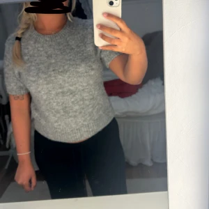 Grå stickad tröja Gina Tricot - Mysig grå stickad tröja från Gina Tricot i storlek S. Tröjan har korta ärmar, rund hals och ribbade muddar vid hals och nederkant. Perfekt för lager-på-lager och chill dagar. Enkel och stilren design som funkar till allt.