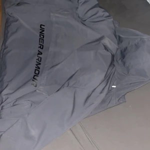 under armour jacka - säljer en under armour windbreaker jacka riktigt skönt nu när det blåser den ger en extra touch på stilen även bra om man ska ut och springa 