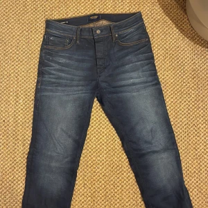Mörkblå jeans från Jack & Jones - Snygga mörkblå jeans från Jack & Jones med klassisk femficksdesign och kontrastsömmar. Jeansen är i modellen slim/straight Tim och är tillverkade i mjukt denimtyg med lätt tvättade detaljer framtill och bak. Perfekta för en avslappnad och stilren look. Storlek 31/32 men midjan sitter mer som 30. Inte använda mer än 5 gånger.