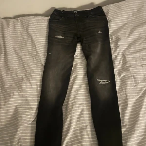 Svarta slim jeans Jack & Jones - Svarta slim fit jeans från Jack & Jones, modell Glenn. Jeansen har slitna detaljer på låren och knäna för en cool look. Klassisk femficksdesign och knappgylf. Materialet är mjukt och stretchigt för extra komfort. Köpta helt nya och bara använt de några gånger! 