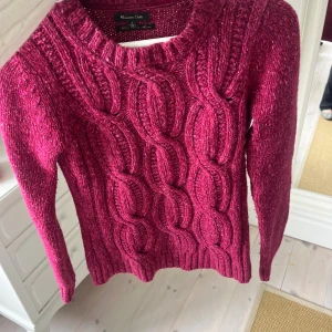 Vinröd stickad tröja Massimo Dutti - Snygg vinröd stickad tröja från Massimo Dutti med grov kabelstickning framtill och ribbade muddar. Rund hals och långärmad modell, perfekt för dig som gillar en klassisk men ändå trendig look.