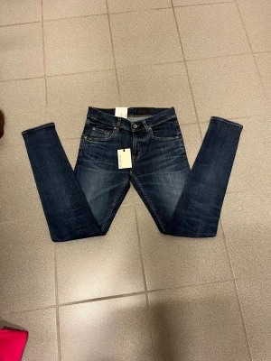 Mörkblå slimmade jeans från Tiger of sweden  W29 L32 - Snygga mörkblå slimmade jeans från T/J med smal passform och slitningar vid benen. Klassisk femficksmodell, bruna sömmar och läderpatch bak i midjan. Perfekta för dig som gillar tajta jeans med lite edge.