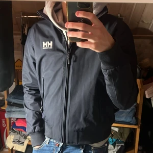 Helly Hansen jacka - Säljer denna riktigt snygga jackan från Helly Hansen. Jackan är i storlek S och är i fint skick, inga defekter. Det står Helly Hansen på armen, se bild. Bara att skriva över frågor och funderingar.