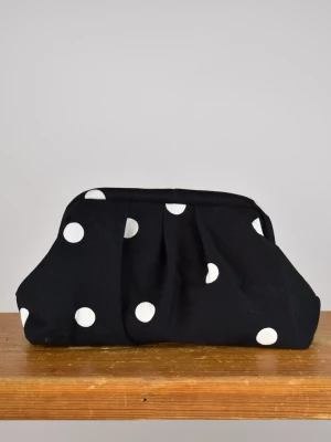 Clutchväska  - Clutchväska, perfekt till fest och vardag.  Denna väskan är gjord av svarta jeans med vita prickar och grått möbeltyg på insidan. Innuti finns en ficka där du kan lägga småsaker och du stänger enkelt med clutch ramen. Clutchram ca 18cm bredd, bredd nertill ca 25cm, höjd ca 15cm. 