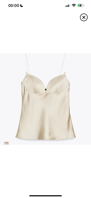 Zara Satin Fest stopp - Säljer en elegant champagnefärgad linnetopp i satin med tunna axelband och formade kupor. Toppen har en slät, glansig yta och en figurnära passform som ger en lyxig känsla. Perfekt för dig som vill ha en stilren och trendig look. Säljer då den inte satt bra på mig🫶🏼använd en gång