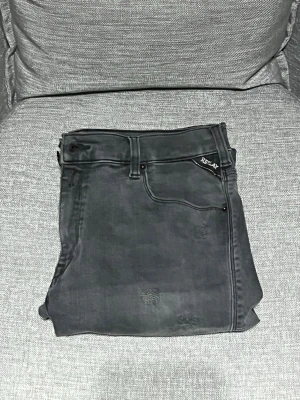 Replay svarta skinny jeans med slitningar - Säljer ett par svarta Replay jeans i skinny fit med coola slitningar och detaljer på benen. Materialet är mjukt och stretchigt jeans, perfekt för dig som gillar en smal siluett. Skriv om frågor eller funderingar, pris kan diskuteras.