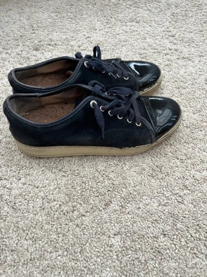Lanvin Patent Cap Toe Sneaker Navy - Säljer mina välanvända och slitna Lanvins till någon som känner att de kan få användning av de. Skorna är slitna (se bilder), men ser schyssta ut ändå. Passar som skor för utekväll, om man vill ha ett par slitskor eller snarlikt. Har bytt ut original sulan mot ett par andra i och med att de var för slitna.  Nypris 4500kr  Köpta på NK i Stockholm  Storlek UK 8 (42 i EU)  Hojta till om du vill ha fler bilder eller funderar över något :)