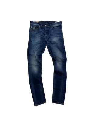 Blå Diesel Buster jeans tapered fit - Snygga blå jeans från Diesel, modell Buster med tapered fit. Klassisk femficksdesign, ljusare tvättade partier och kontrastsömmar. Jeansens material är bomull med en skön känsla och passformen är normal. Perfekt för dig som gillar stilrena och moderna jeans.
