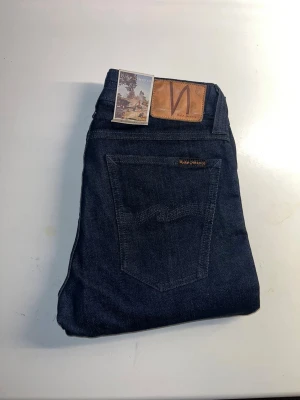 Nudie Jeans  - Helt nya! Säljer ett par mörkblå Skinny Lin jeans från Nudie Jeans. Modellen är skinny fit med smal passform. Midja 32cm, längd 106cm. JAG SKICKAR EJ FLER BILDER NÄR JAG BÄR JEANSEN! för storleksguide hänvisar jag till måtten och för bättre inblick i passformen rekommenderar jag att googla på modellnamnet. kolla måtten noggrant :) s5,1