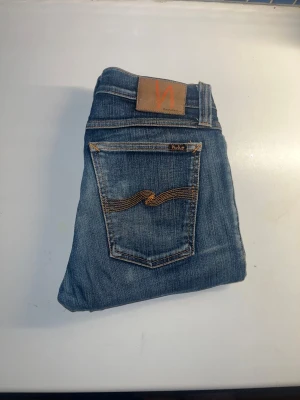 Nudie Jeans  - Säljer ett par Nudie Jeans Tight Long John i färgen dark superb blue. Klassiska blå jeans med skinny passform, tillverkade i bomull och elastan för extra stretch och komfort. Midja 36cm, längd 101cm. JAG SKICKAR EJ FLER BILDER NÄR JAG BÄR JEANSEN! för storleksguide hänvisar jag till måtten och för bättre inblick i passformen rekommenderar jag att googla på modellnamnet. kolla måtten noggrant :) s5 