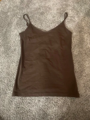 Brun linnetopp från 157 i XS - Säljer en enkel brun linnetopp från 157 i storlek XS. Toppen har smala axelband och är tillverkad i mjuk bomull med lite stretch för skön passform. Perfekt att styla med jeans eller kjol för en chill look.