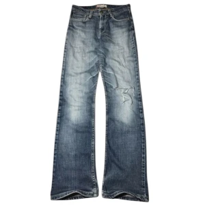 Blå jeans 627 Straight Fit - Säljer ett par blå jeans med straight fit och slitningar på ena benet. Modellen är 627 och har klassiska fem fickor, knappstängning och kontrastsömmar. Jeansen har en cool tvättad look och är tillverkade i jeansmaterial.                         Storlek 28/32