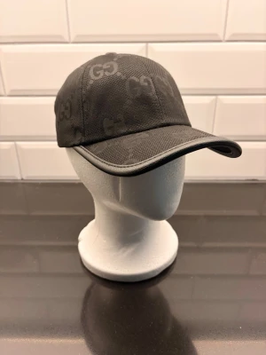 Svart keps från Zara - Snygg svart keps från med klassiskt GG-mönster över hela kepsen. Kepsen har böjd skärm, justerbar rem baktill och är tillverkad i ett slitstarkt material. Perfekt accessoar för en trendig look.