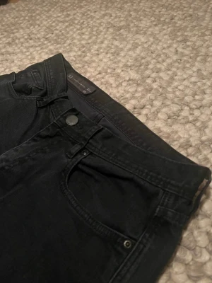 Svarta Armani Exchange Skinnyfit - Svarta jeans från Armani Exchange i skinny fit med klassisk femficksdesign och metallknapp fram. Snyggt AX-emblem på bakfickan och stilren look. Materialet är jeans och passformen är tight. 