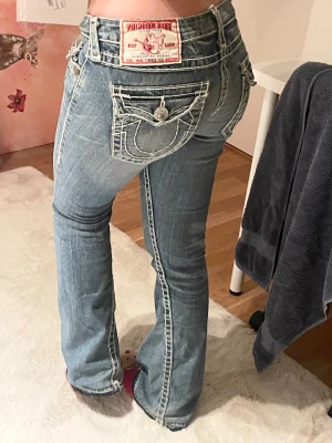 Vintage True Religion ljusblå bootcut jeans - Vintage superlågmidjade bootcut jeans från true religion med vita sömmar. Innerbenslängden är ca 78cm och midjemåttet är ca 39 cm tvärsöver! Bara att skriva för fler bilder eller om frågor🩷